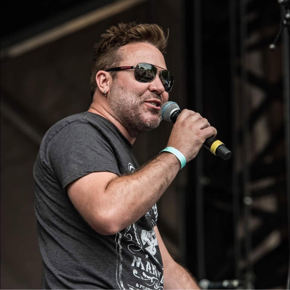 Brian West speaking into a microphone on stage